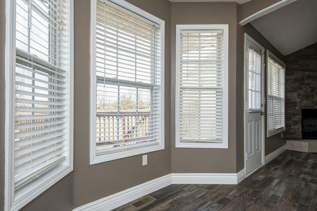 interior space with visible vents, baseboards, a healthy amount of sunlight, and dark wood-style flooring