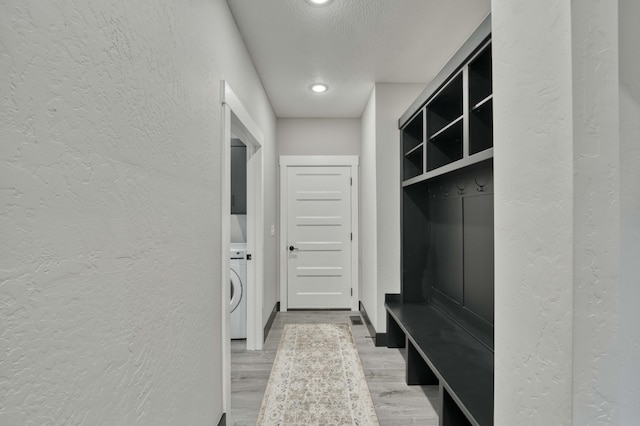 mudroom with a textured ceiling, washer / dryer, light wood-style flooring, and a textured wall