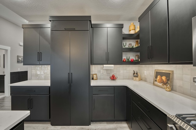 kitchen with decorative backsplash, light countertops, open shelves, and a textured ceiling