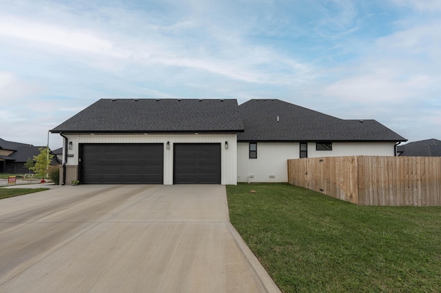 view of front of property with fence, driveway, roof with shingles, a front lawn, and a garage