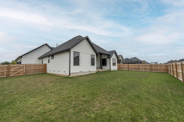 rear view of house with a lawn and a fenced backyard