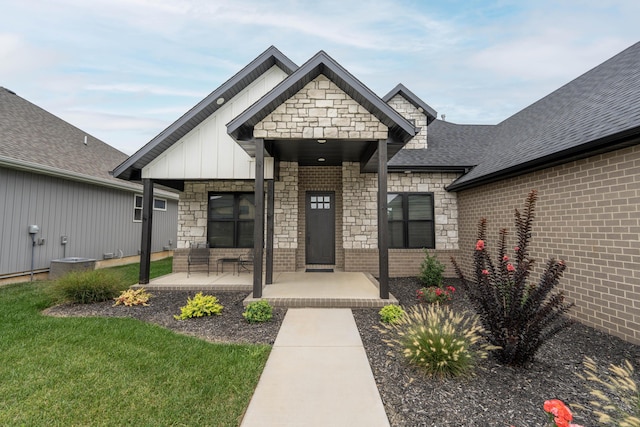 view of front of house featuring a front lawn, stone siding, a porch, board and batten siding, and a shingled roof