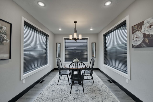 dining area with an inviting chandelier, wood finished floors, baseboards, and visible vents