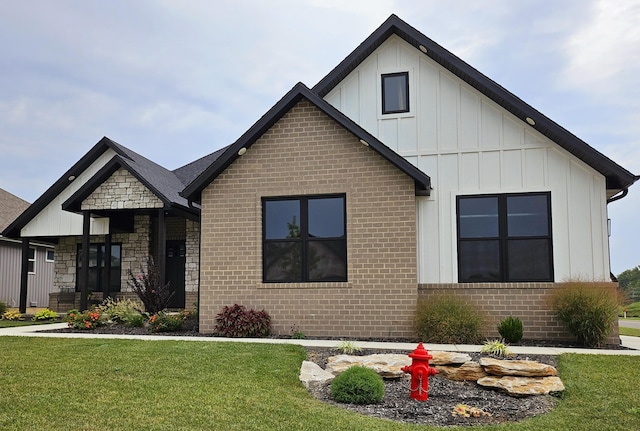 modern farmhouse with a front lawn, brick siding, and board and batten siding