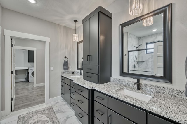 full bathroom with washer / dryer, a notable chandelier, marble finish floor, and a sink