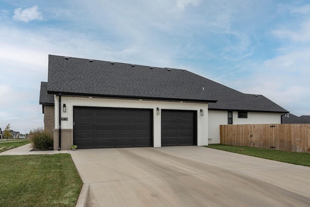 view of front facade featuring fence, roof with shingles, concrete driveway, a garage, and brick siding