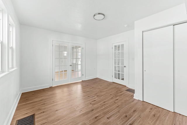 interior space with wood finished floors, french doors, and visible vents