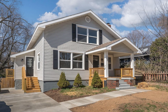 view of front of property featuring fence, a porch, a chimney, and entry steps