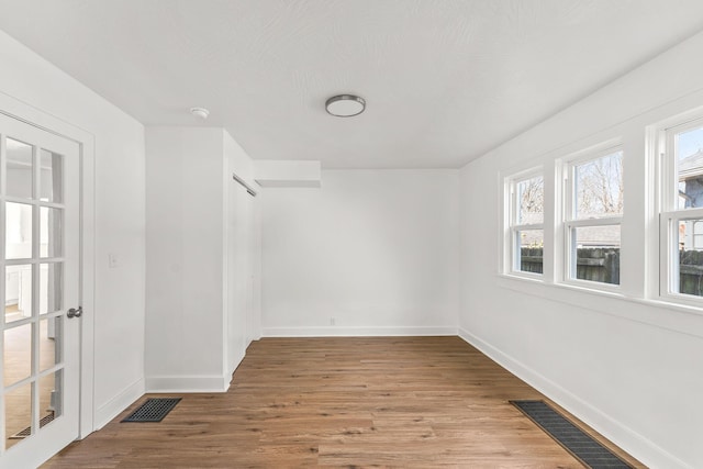 empty room with visible vents, baseboards, and wood finished floors