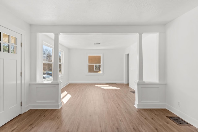 interior space with visible vents, light wood-style flooring, and ornate columns