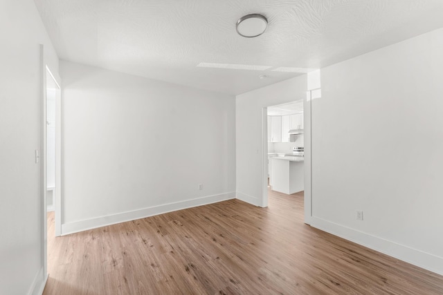 empty room with wood finished floors, baseboards, and a textured ceiling