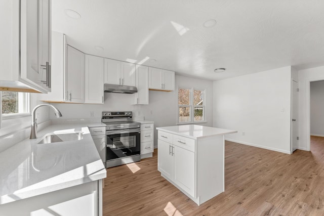 kitchen with under cabinet range hood, stainless steel range with electric stovetop, white cabinetry, and a sink