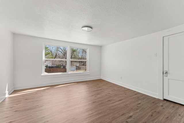 unfurnished room featuring baseboards, a textured ceiling, and wood finished floors