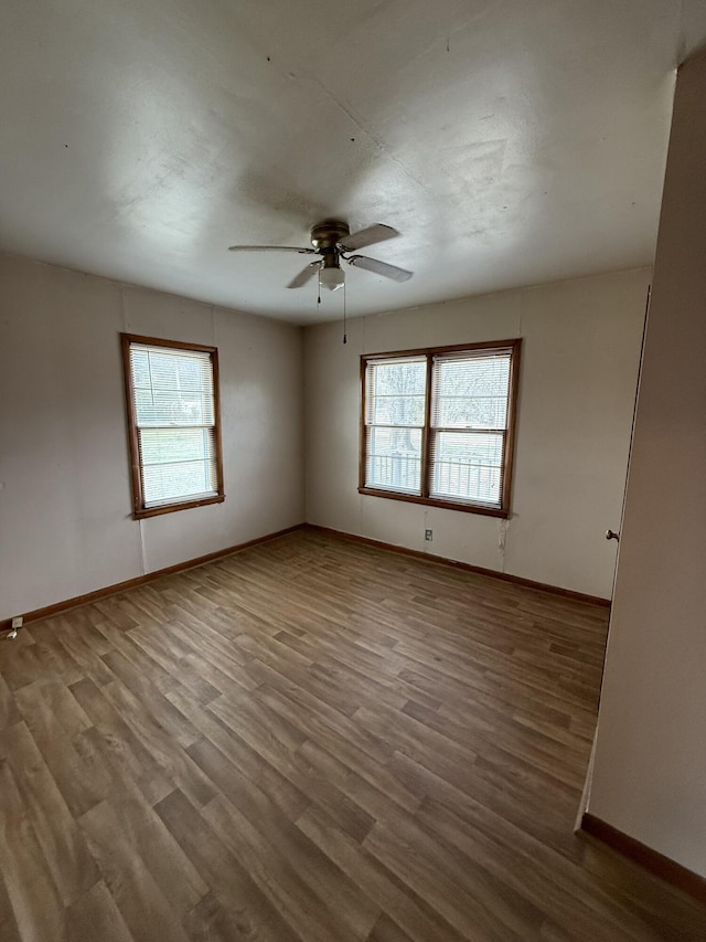 unfurnished room with a wealth of natural light, ceiling fan, and wood finished floors