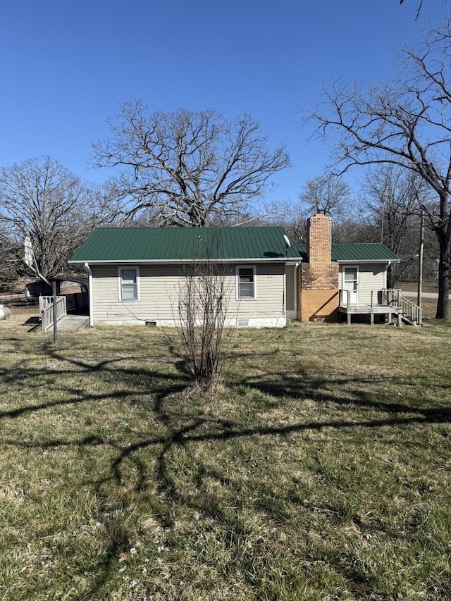 view of side of home with metal roof, a yard, a deck, and a chimney