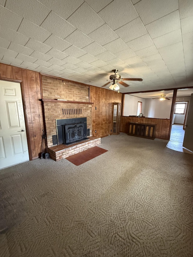 unfurnished living room with a ceiling fan, carpet, and wood walls