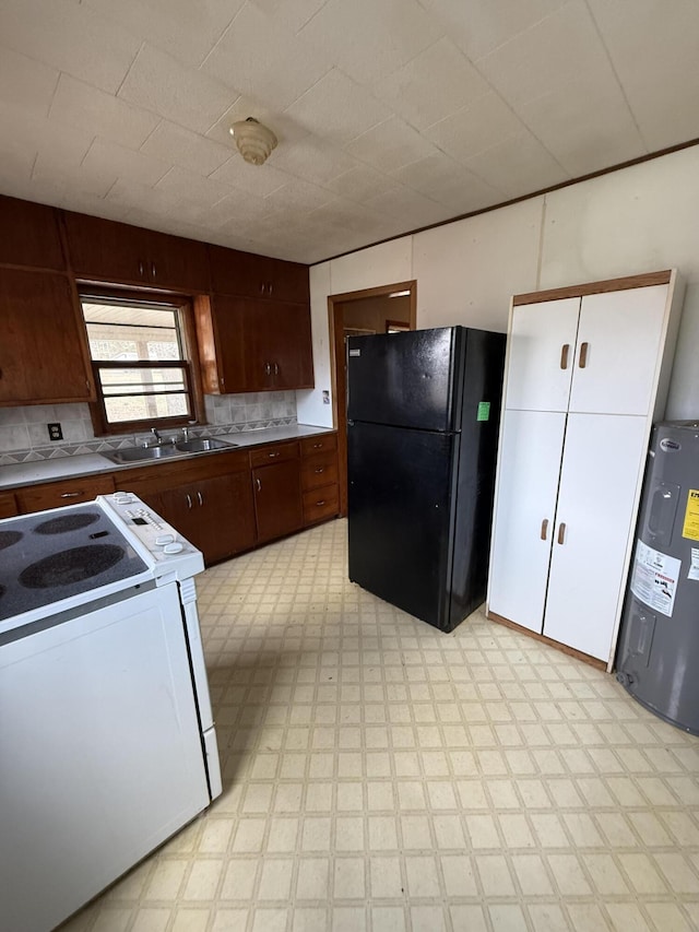 kitchen with electric water heater, light floors, freestanding refrigerator, white electric range, and a sink