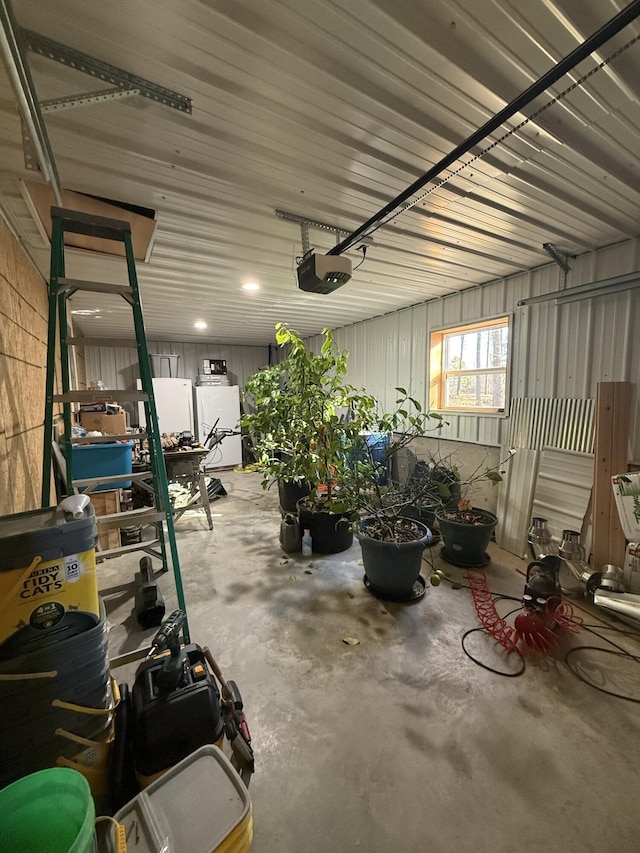 garage featuring freestanding refrigerator, metal wall, and a garage door opener