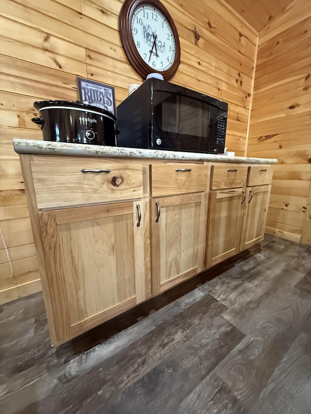 interior details featuring wooden walls, black microwave, and wood finished floors