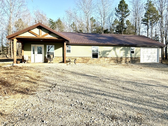 exterior space featuring stone siding, driveway, and metal roof