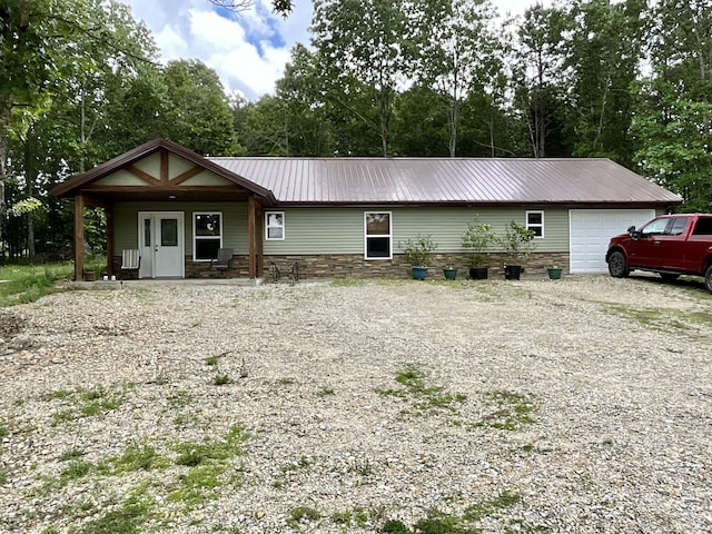 2887 County Road 5620, Willow Springs, MO 65793 - view of front facade with metal roof, covered porch, driveway, an attached garage, and stone siding