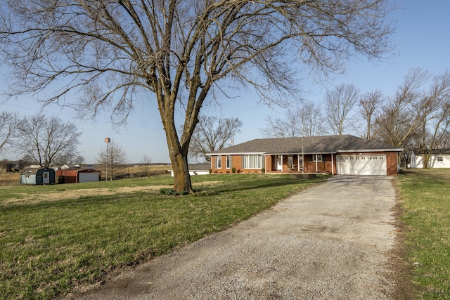 view of front of home with a shed, concrete driveway, a front yard, an outbuilding, and an attached garage