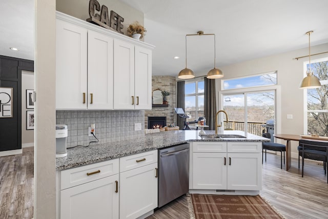 kitchen featuring a sink, white cabinetry, a peninsula, decorative backsplash, and dishwasher