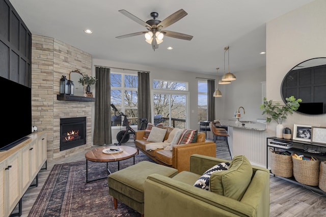 living area featuring a ceiling fan, wood finished floors, recessed lighting, and a fireplace