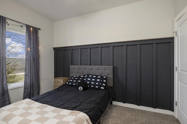 carpeted bedroom featuring a decorative wall and a wainscoted wall