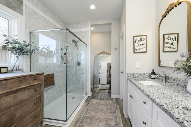 bathroom with wood finished floors, a stall shower, and vanity