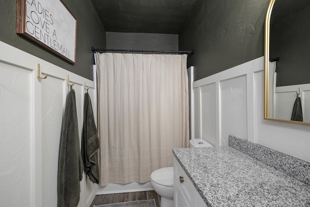 full bath featuring shower / tub combo with curtain, toilet, wood finished floors, and vanity