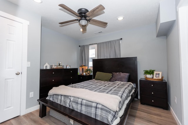 bedroom featuring a ceiling fan, visible vents, wood finished floors, and baseboards