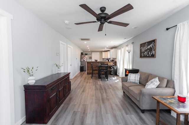 living room featuring visible vents, light wood-style flooring, a ceiling fan, recessed lighting, and baseboards