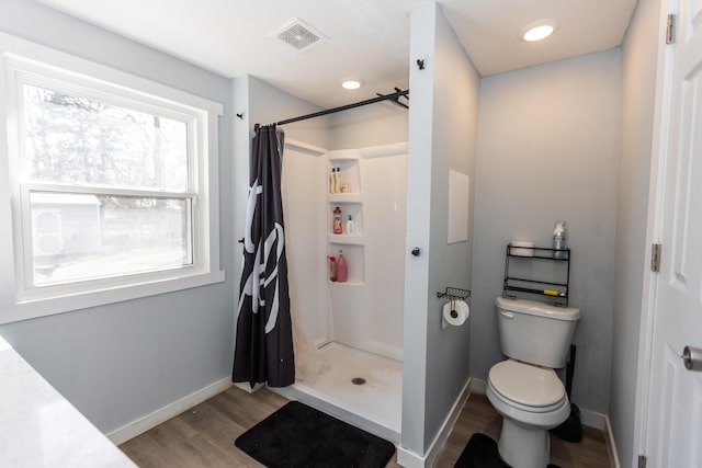 full bathroom with visible vents, toilet, wood finished floors, a shower stall, and baseboards