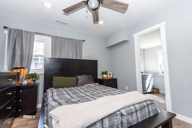 bedroom featuring visible vents, baseboards, wood finished floors, and a ceiling fan