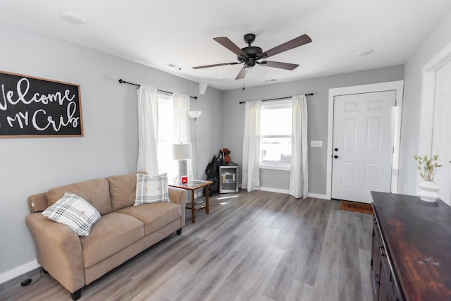 living area featuring visible vents, baseboards, ceiling fan, and wood finished floors