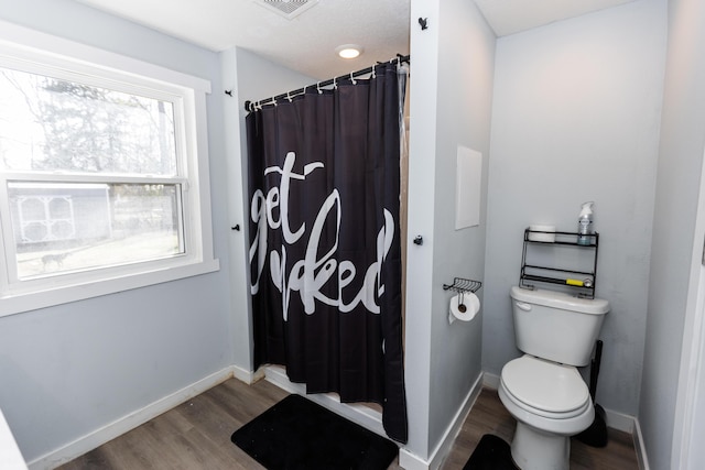 full bath with a shower with curtain, wood finished floors, visible vents, baseboards, and toilet