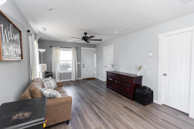 living room featuring baseboards, wood finished floors, and a ceiling fan