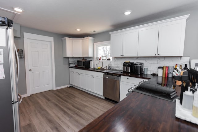 kitchen featuring tasteful backsplash, dark wood finished floors, white cabinets, stainless steel appliances, and a sink