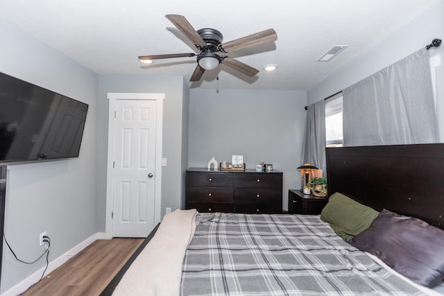 bedroom featuring ceiling fan, wood finished floors, visible vents, and baseboards