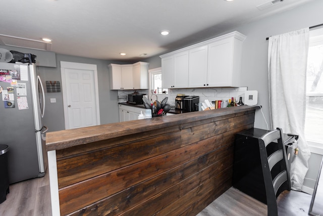 kitchen with backsplash, white cabinets, and freestanding refrigerator