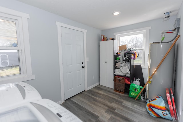 clothes washing area with water heater, laundry area, baseboards, and wood finished floors