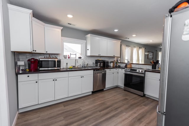 kitchen featuring dark countertops, visible vents, appliances with stainless steel finishes, and a sink