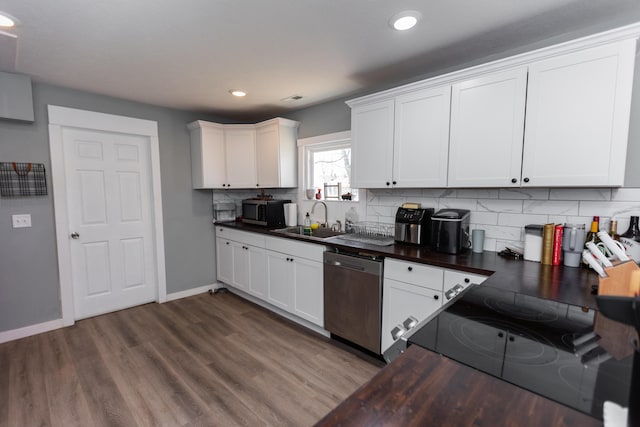 kitchen featuring a sink, stainless steel appliances, dark wood-type flooring, dark countertops, and backsplash