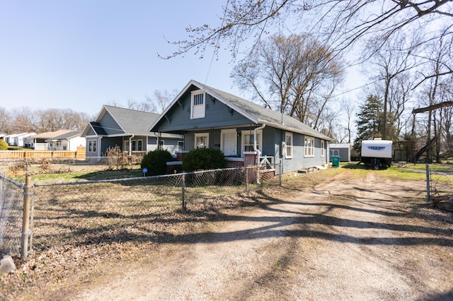 bungalow-style home featuring a fenced front yard and dirt driveway