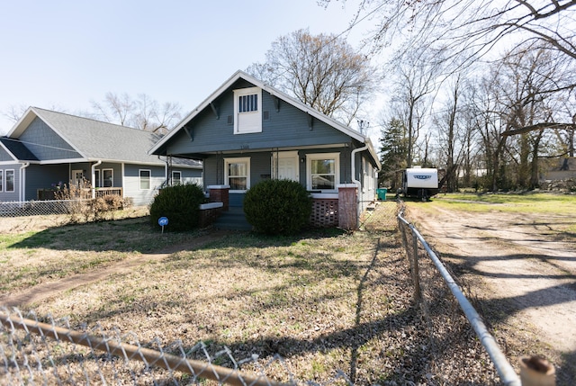 bungalow featuring a front lawn, fence, covered porch, and driveway