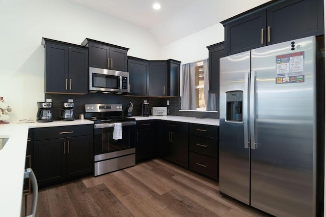 kitchen featuring tasteful backsplash, dark wood finished floors, stainless steel appliances, and light countertops