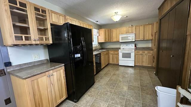 kitchen featuring dark countertops, black appliances, glass insert cabinets, and a sink