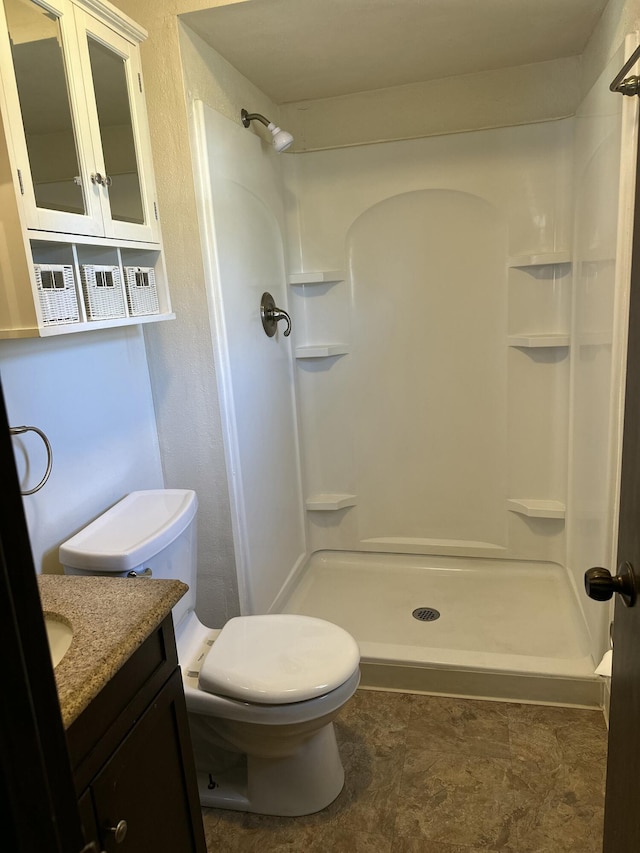 full bathroom with vanity, a shower stall, and toilet