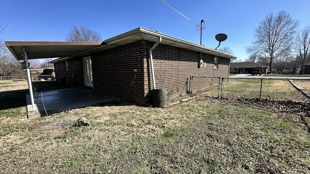 view of side of property featuring a patio, brick siding, and fence